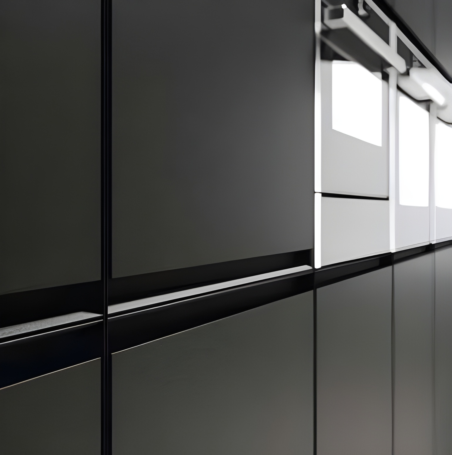 Gros plan sur des armoires de cuisine modernes, de couleur foncée, avec des poignées épurées et minimalistes et des surfaces lisses et réfléchissantes, parfaites pour une cuisine haut de gamme.